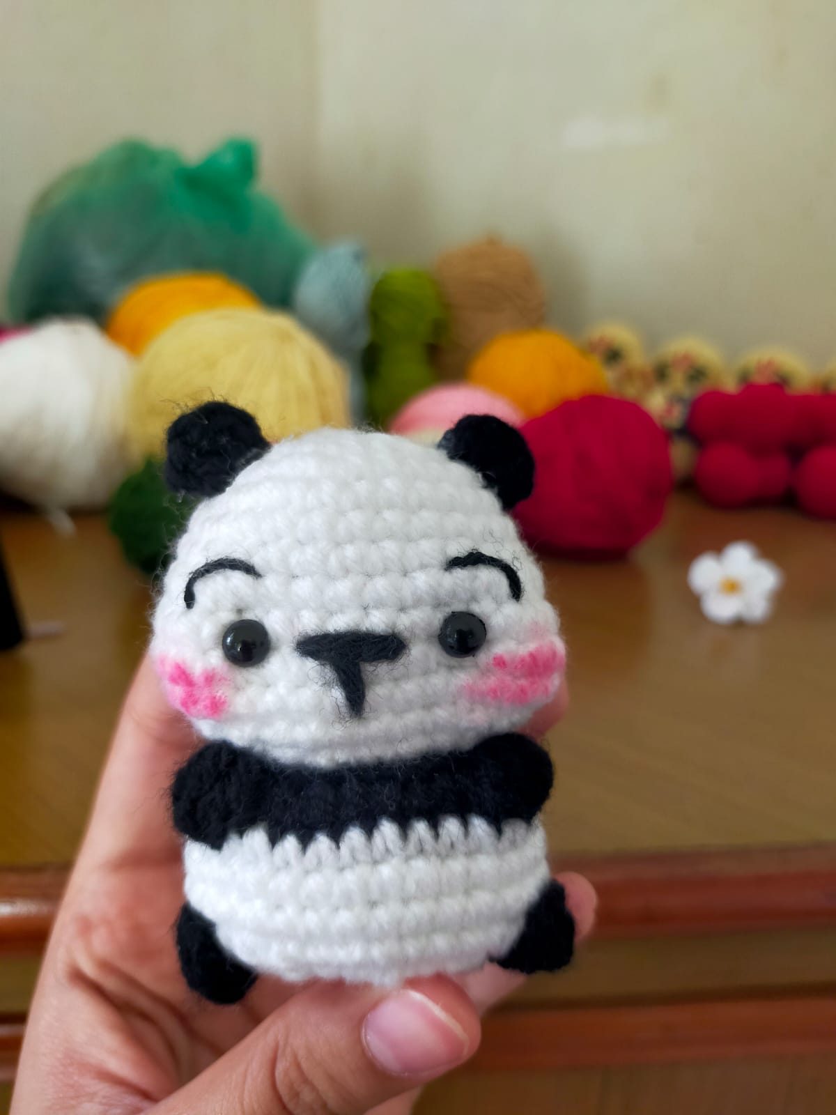 Small crocheted panda amigurumi with blushed cheeks